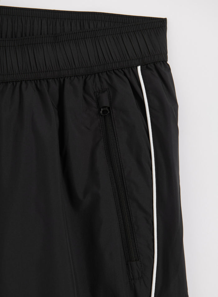 Black aim'n Balance Tracksuit Pants featuring a functional zippered pocket and white side piping.