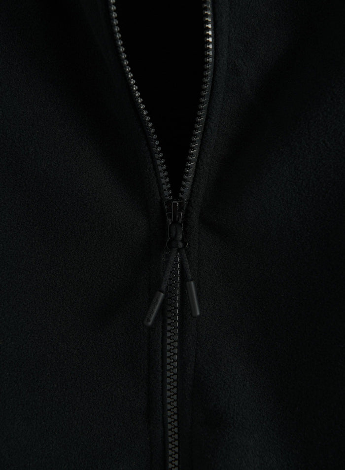 Close-up of a black fleece zip jacket showing the front zipper