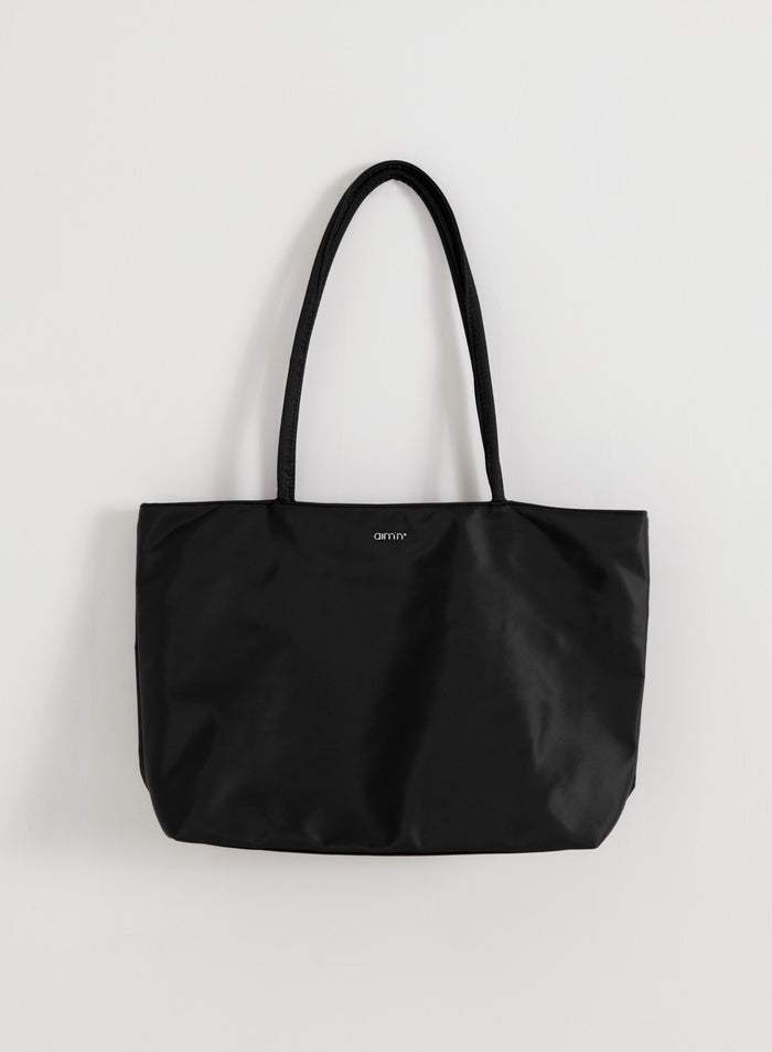 Black nylon tote bag from aim'n with long shoulder straps and a small logo on the front.
