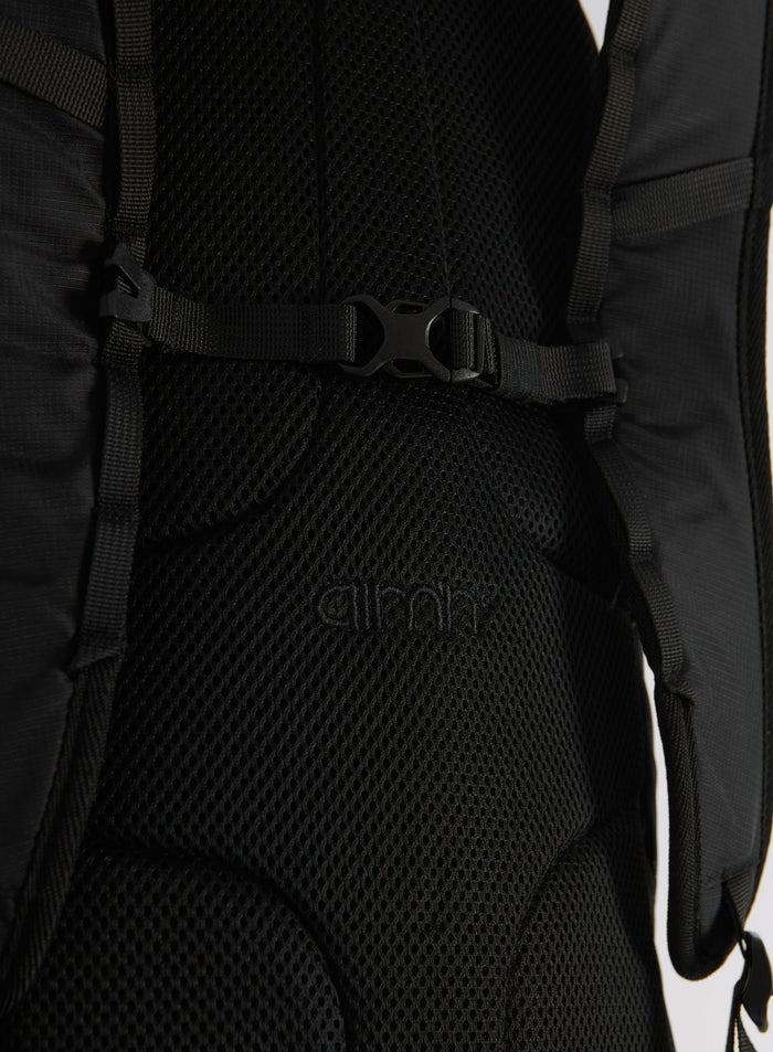 Close-up detail of the back padding and strap buckle of the black Outdoor Daypack with the aim'n logo
