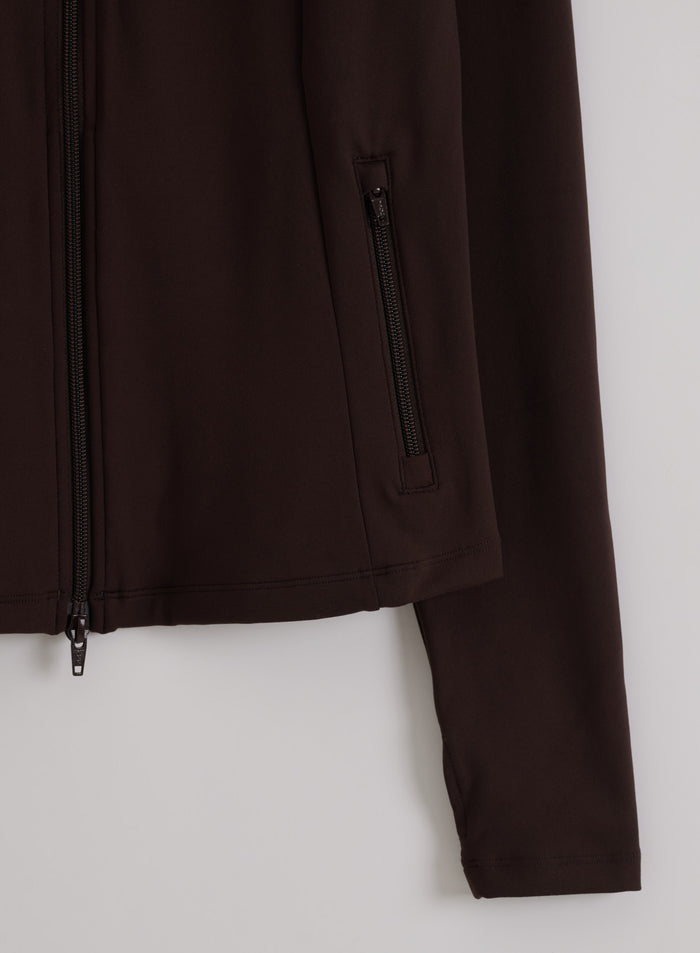 Detailed view of the chocolate brown Sense Zip Jacket by aim'n, featuring a two-way zipper and zipped pocket.