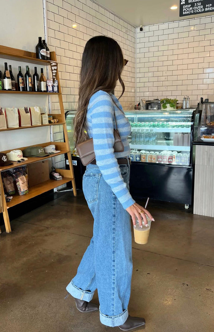 Side view of a blue and white striped knit sweater with long sleeves and a cropped, fitted silhouette
