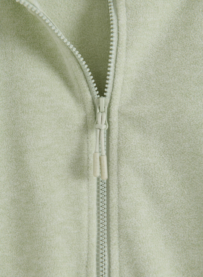 Close-up of the zipper detail on the pistachio-colored fleece zip jacket