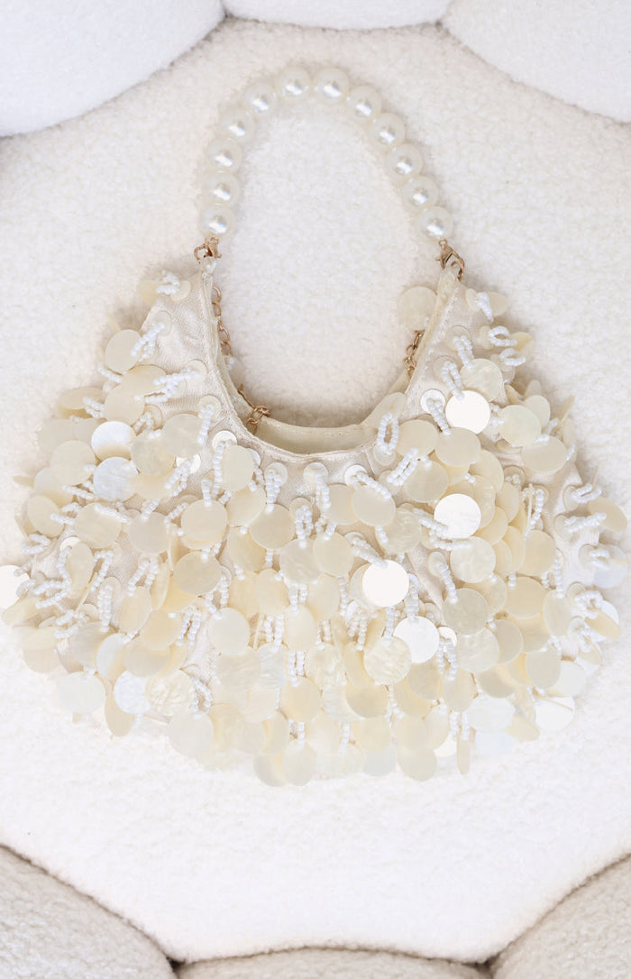 Cream handbag featuring a pearl beaded handle and layered mother-of-pearl disc and seed bead embellishments