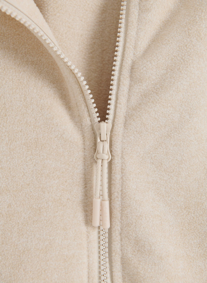 Close-up of the sand fleece zip jacket showing the front zipper and soft fleece texture