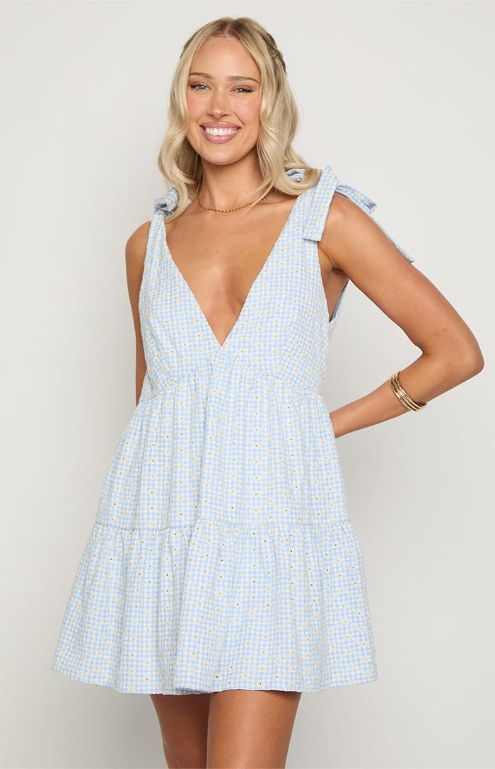Deep V-neckline and tie-shoulder straps of a blue gingham floral mini dress
