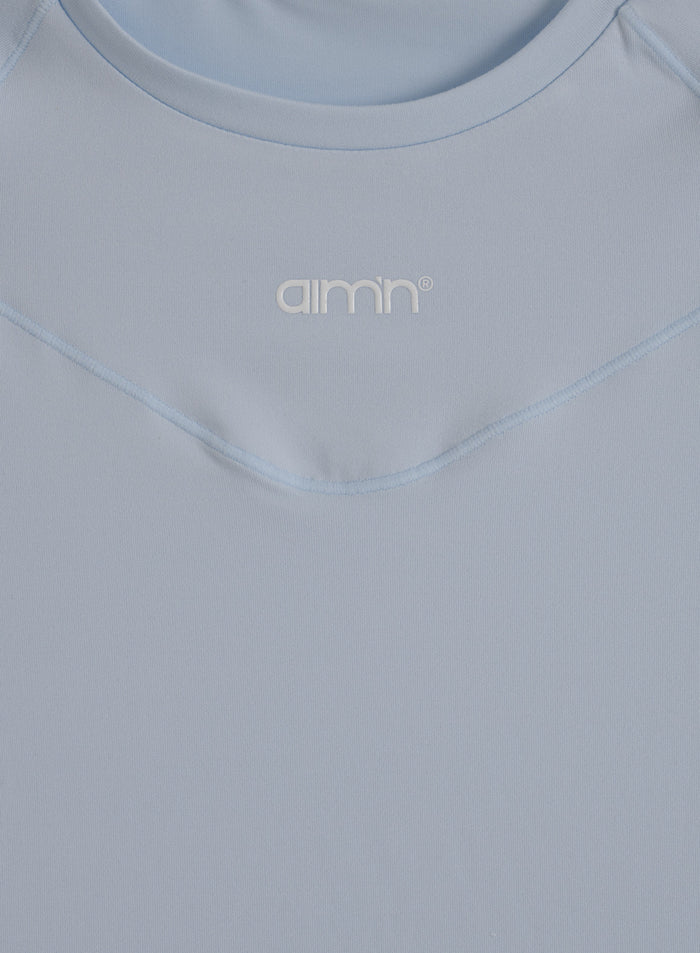 Close-up of the light blue Aura Soft Basic Short Sleeve with a round neck and printed aim'n logo on the chest.