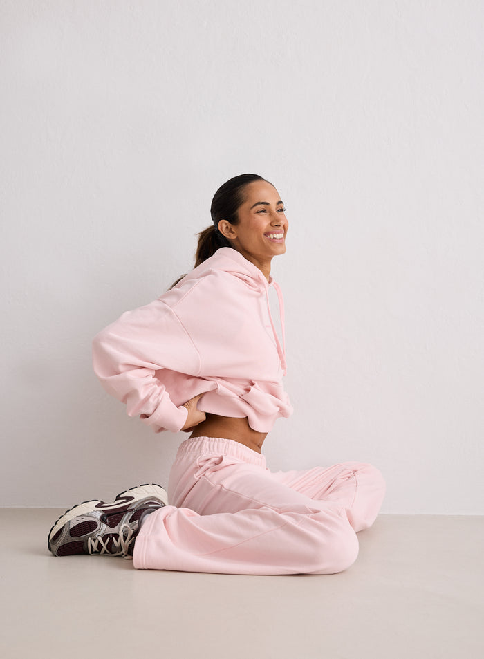 A woman sitting on the floor wearing a pink hoodie and Ballerina Chunky Terry Sweatpants from aim'n [S-170cm]