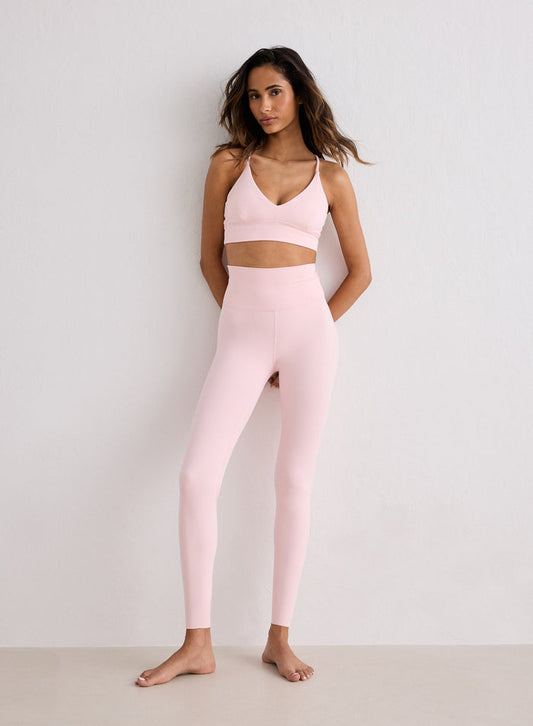 A model wearing ballerina pink Sense Petite Tights and a matching sports bra from aim'n