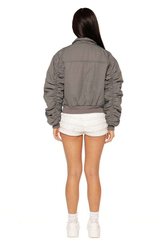 Rear view of a grey bomber jacket with ruched sleeves and a ribbed hem