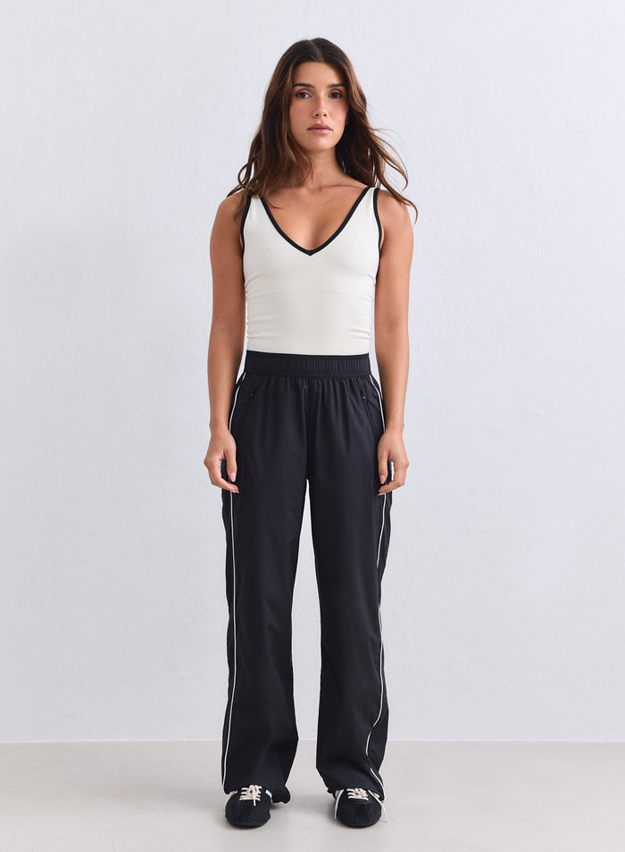 Black aim'n Balance Tracksuit Pants featuring white side piping and a relaxed woven design. [S-165cm]