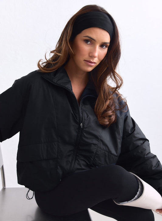 Model sits wearing the black woven Cloud Jacket by aim'n with a headband and leggings. [S-163cm]