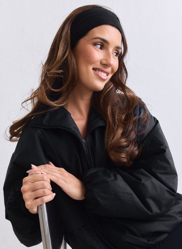 Black aim'n Cloud Jacket worn by a woman sitting on a chair with a headband and leggings. [S-163cm]