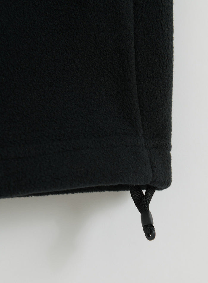 Close-up of black fleece pants fabric with an adjustable drawcord hem