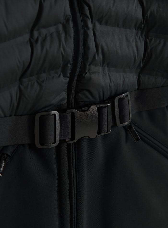Close-up of a black hybrid jacket showing quilted panels, a front zip and an adjustable waist buckle