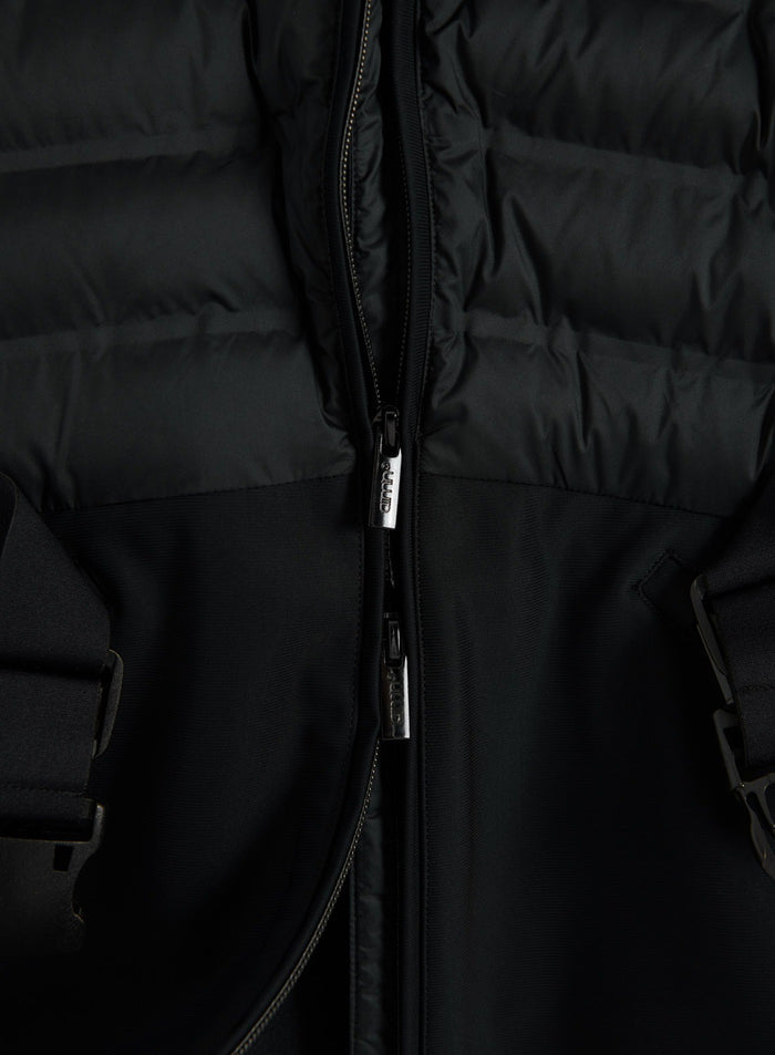 Close-up of a black hybrid jacket with quilted padded panels, a front zip and contrasting stretch fabric
