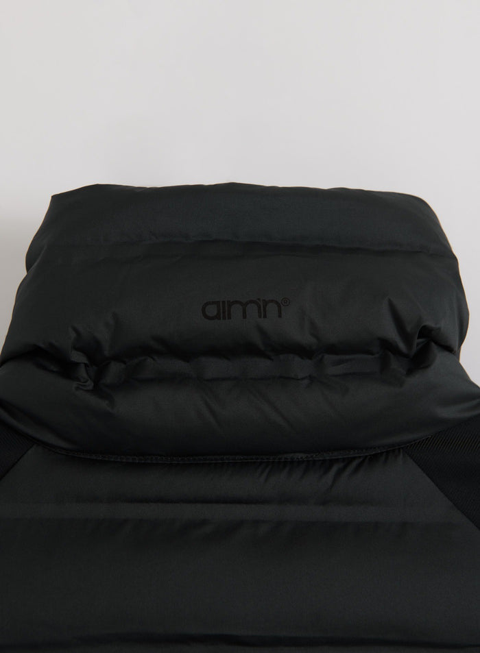 Close-up of a black aim'n Hybrid Jacket laid flat, showing its padded sections and logo