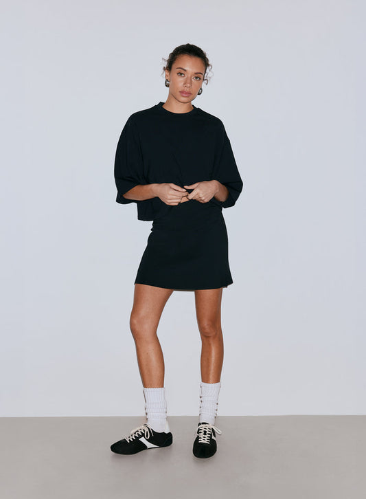A female model wearing a black oversized top and a black mini skort, white socks, and sneakers. [36-170CM]