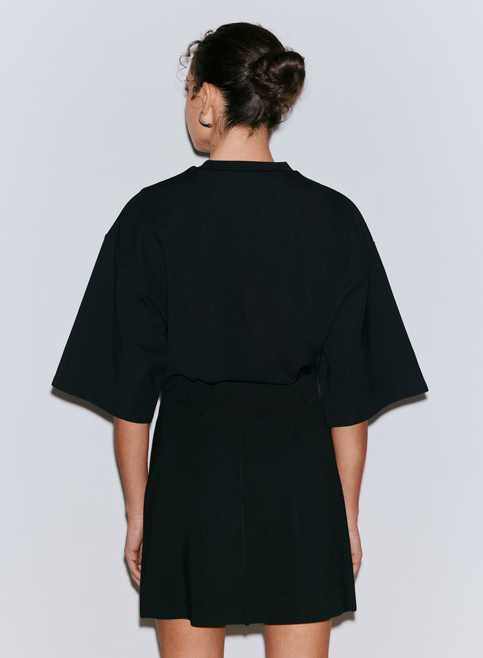 Back view of a woman wearing a black Luxe Mini Skort [36-170CM]