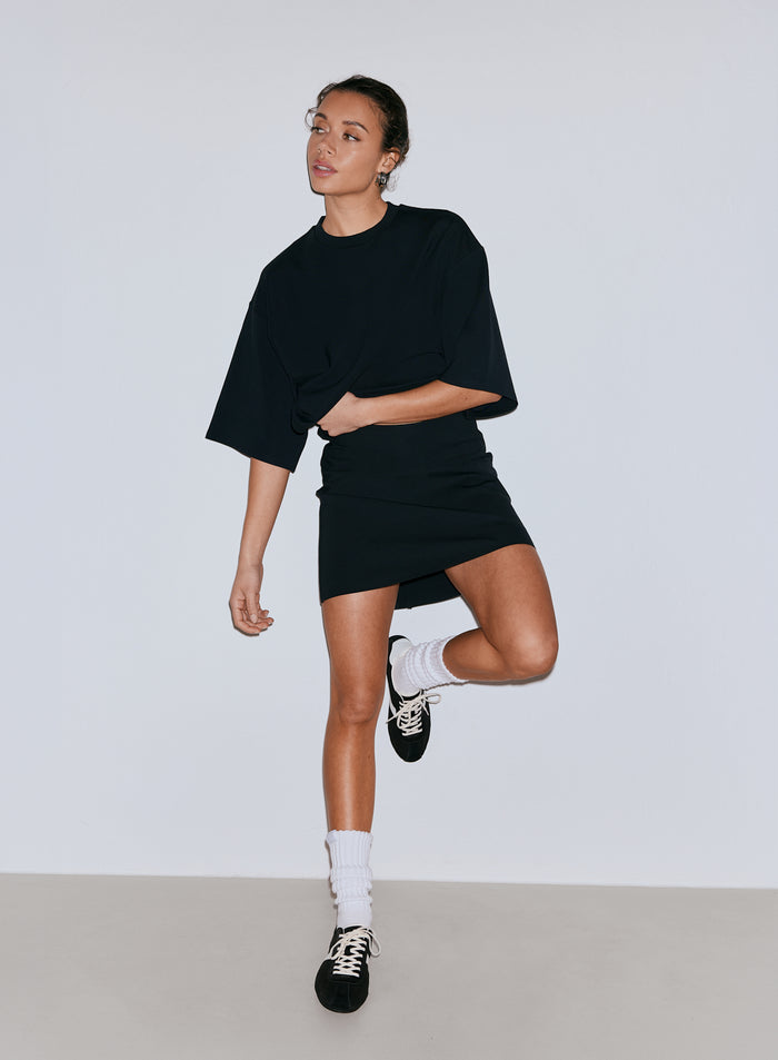 Model wearing a black oversized t-shirt and black Luxe Mini Skort. [36-170CM]