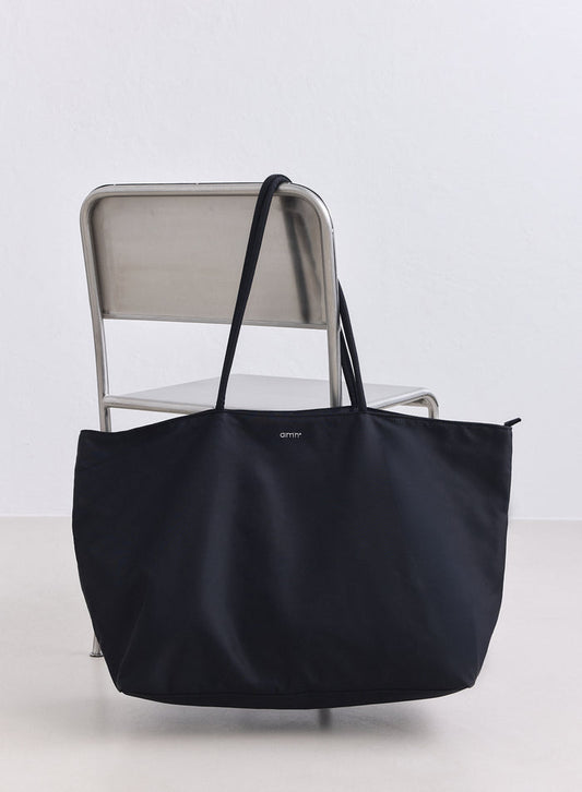 Large black nylon weekend bag featuring the aim'n logo resting on a metal chair.