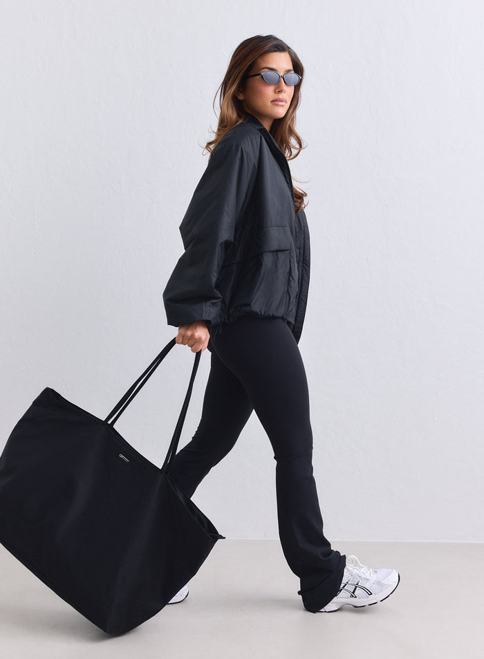 Black nylon weekend bag by aim'n carried by a woman walking in matching activewear