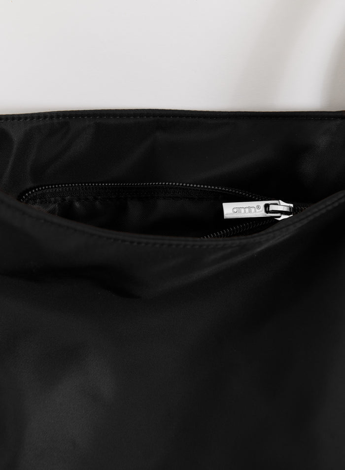 Close-up of a black Nylon Weekend Bag showing an interior pocket with a silver aim'n logo zipper pull.
