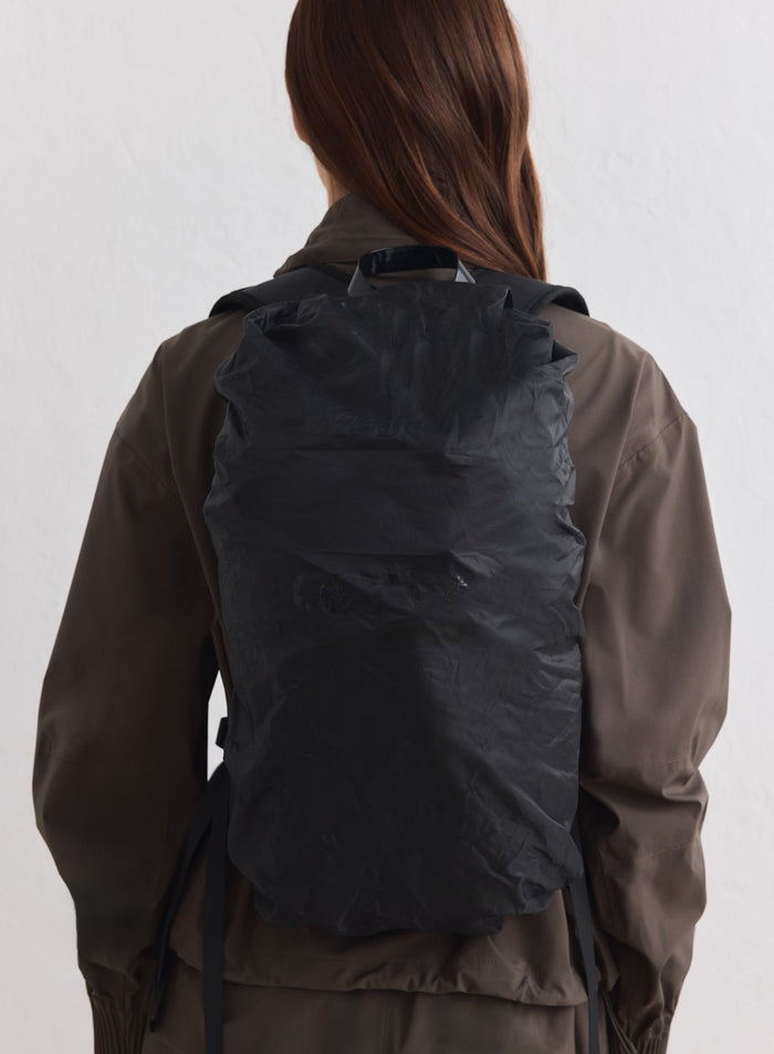 Black aim'n Outdoor Daypack with a crinkled polyester finish worn over an olive jacket.