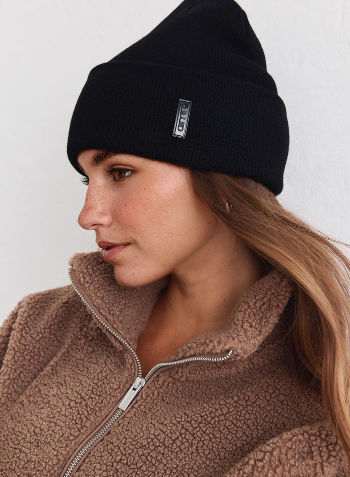 Black knitted aim'n Outdoor Logo Beanie styled with a cozy brown teddy fleece jacket.