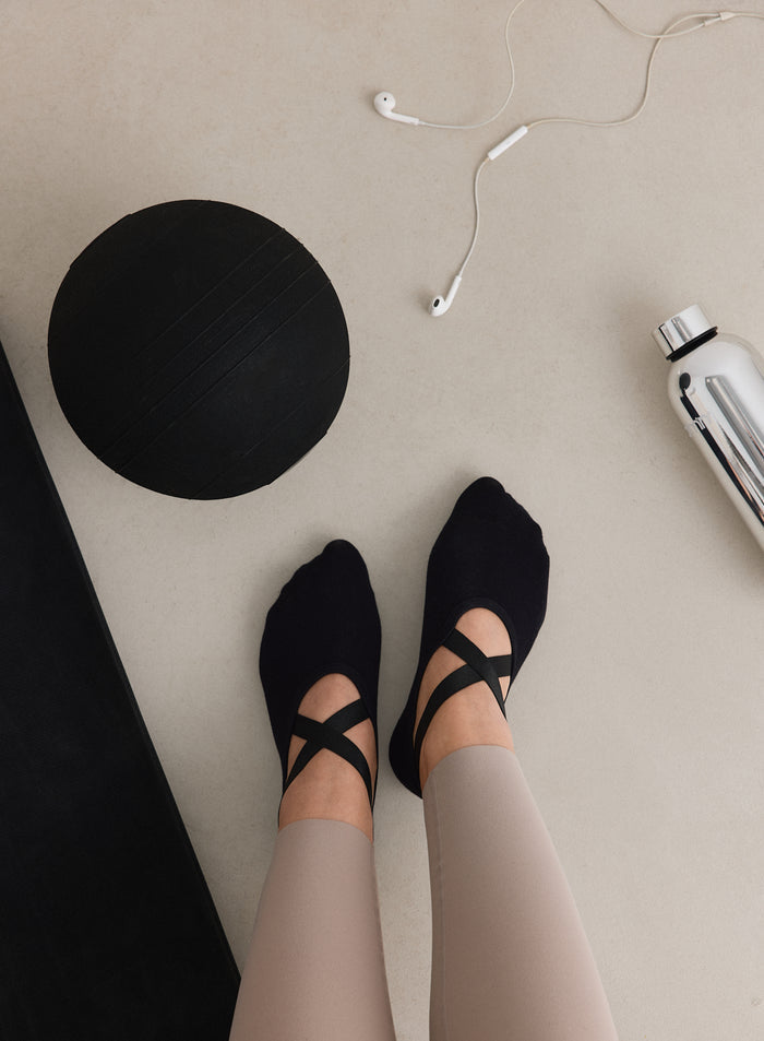 Top-down view of a person wearing black Pilates Socks from aim'n.