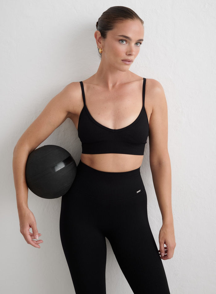 Black aim'n Ribbed Seamless Deep Cut Bra and matching leggings worn while holding a medicine ball. [S-165cm]