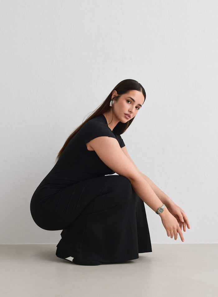 Woman wearing a black Sense Mermaid Cap Sleeve Dress from aim'n crouching down [L-174cm]