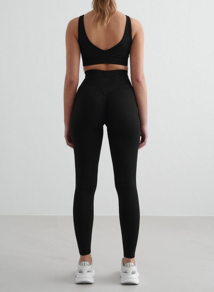Woman wearing black Shape Seamless Tights from aim'n, seen from the back. [S - 175 cm]
