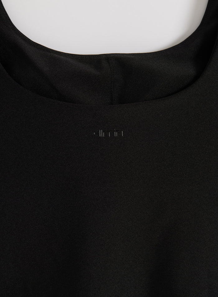 Close-up of the black Shimmer Singlet's neckline featuring a subtle aim'n logo on shimmering fabric.