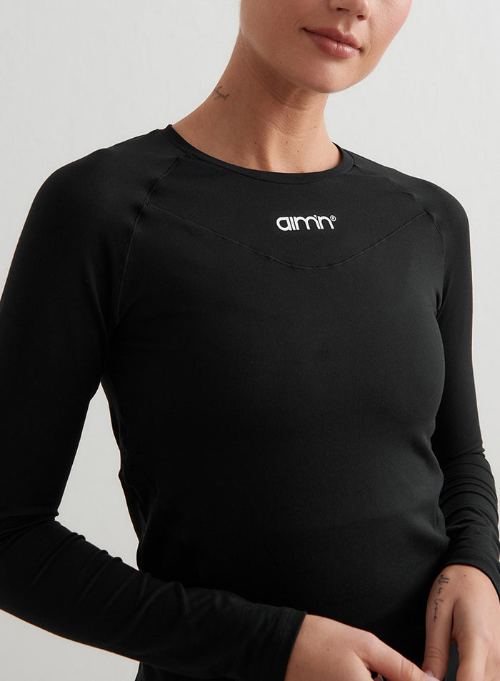 Black Soft Basic Long Sleeve featuring a white aim'n logo, raglan sleeves, and flattering shaping details.