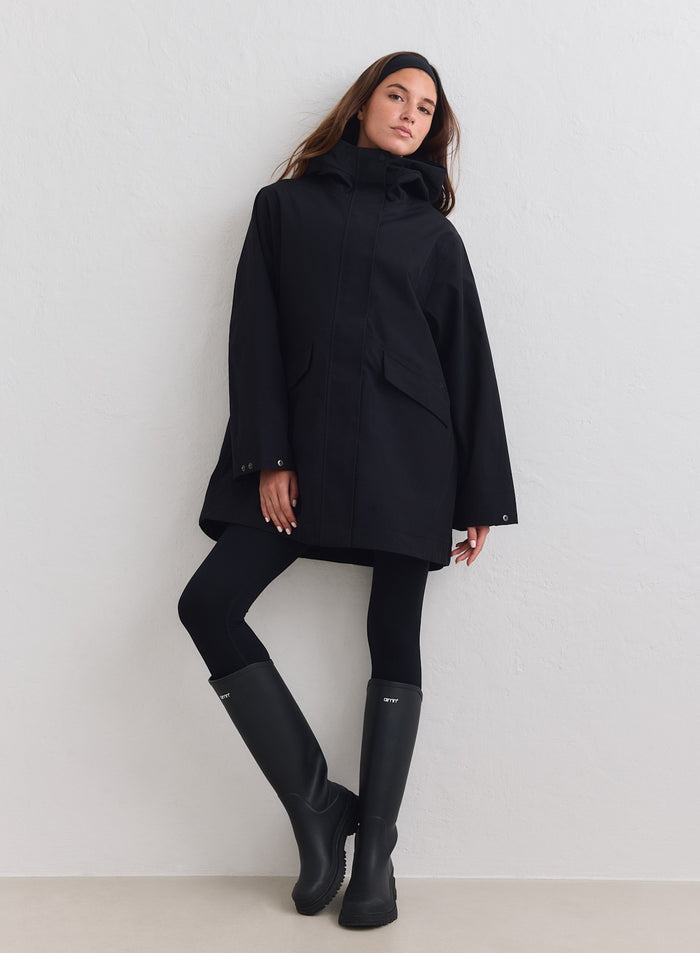 Black waterproof hood jacket worn by a model with leggings and rain boots by aim'n [M-178cm]