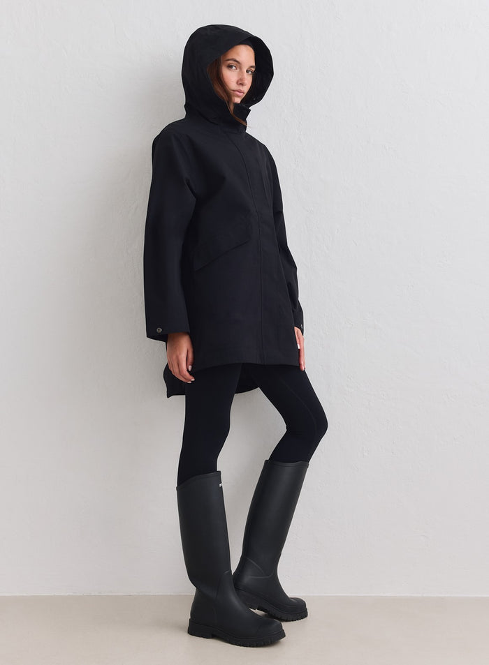 Black aim'n Waterproof Hood Jacket featuring a minimalist design, paired with leggings and tall boots. [M-178cm]