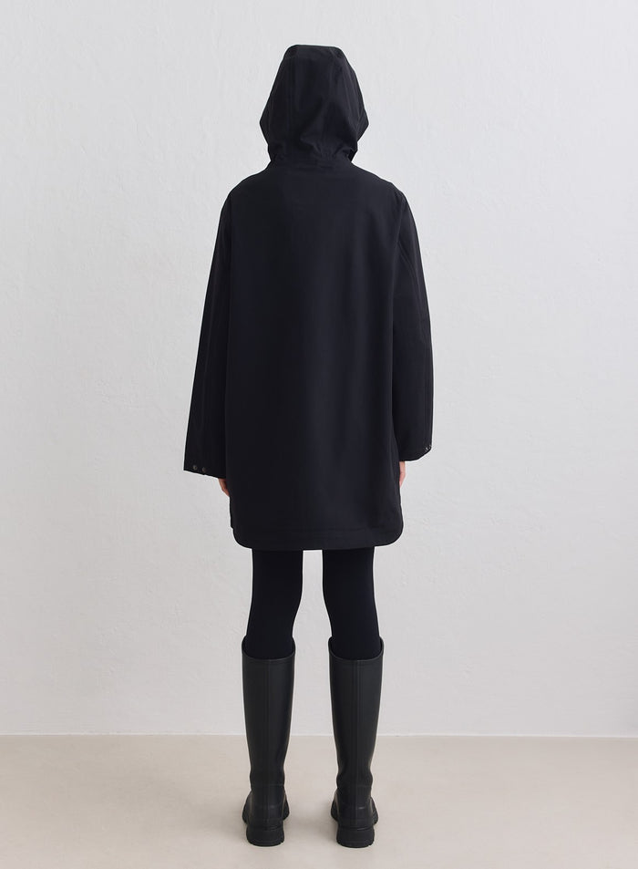 Black aim'n Waterproof Hood Jacket in a long, minimalist design, shown from the back with the hood up. [M-178cm]