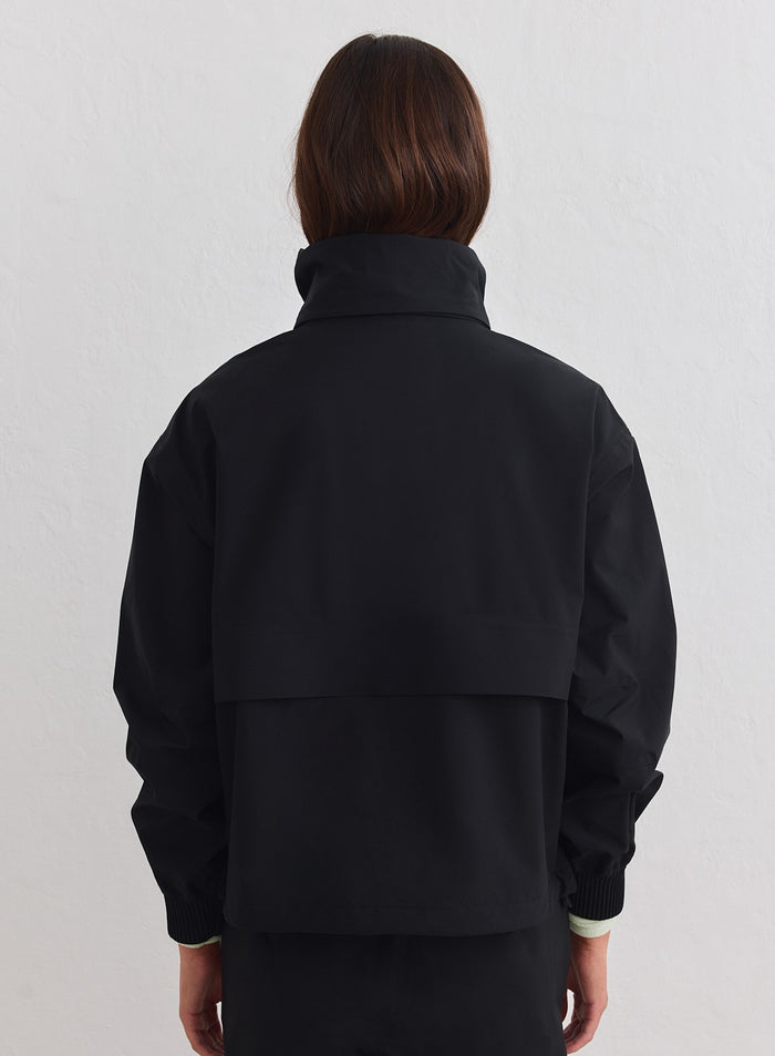 Back view of a black aim'n Waterproof Stretch Anorak featuring a high collar and rear vent. [xs-178cm]