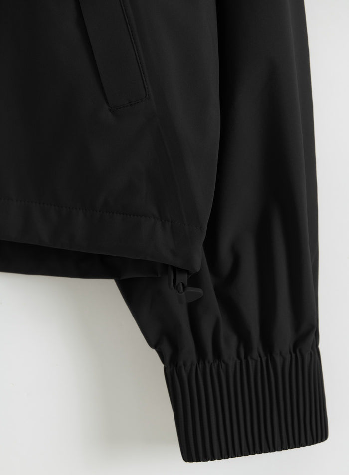Close-up of a black waterproof stretch anorak sleeve with an adjustable toggle and elasticated cuff