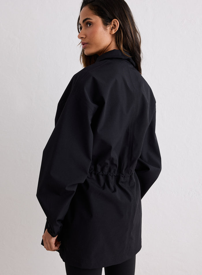 Woman seen from back wearing black waterproof zip jacket with adjustable waist [S-170cm]
