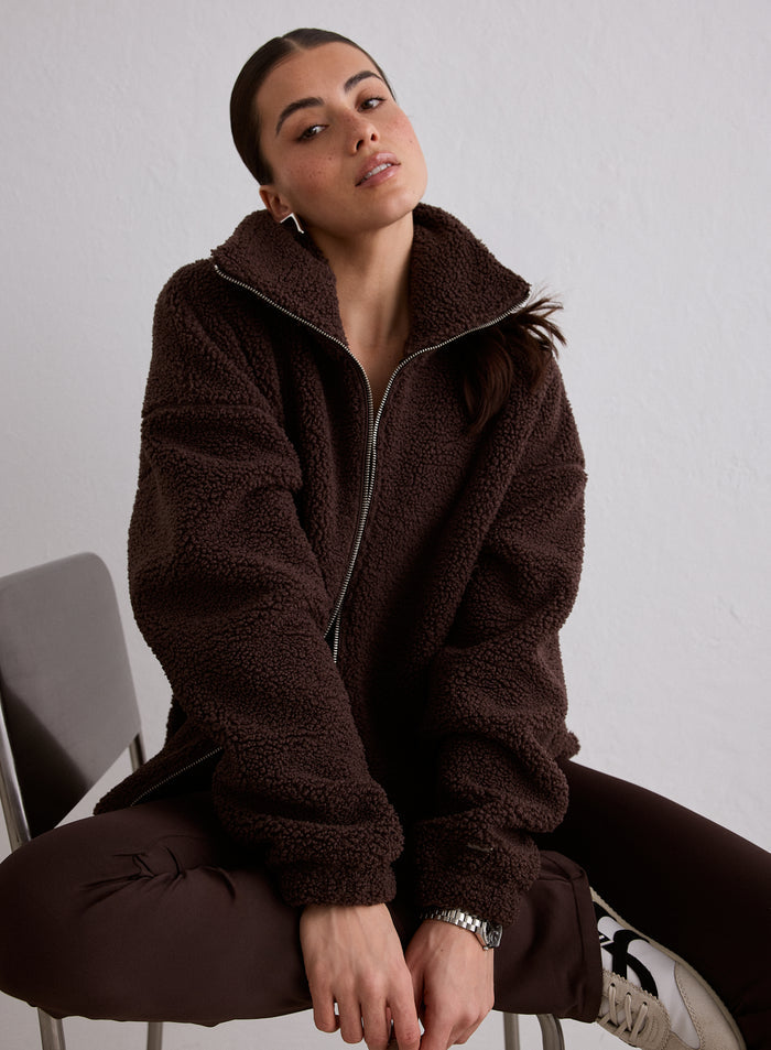 A model sitting on a chair wearing the Cacao Pile Jacket [M-174cm]