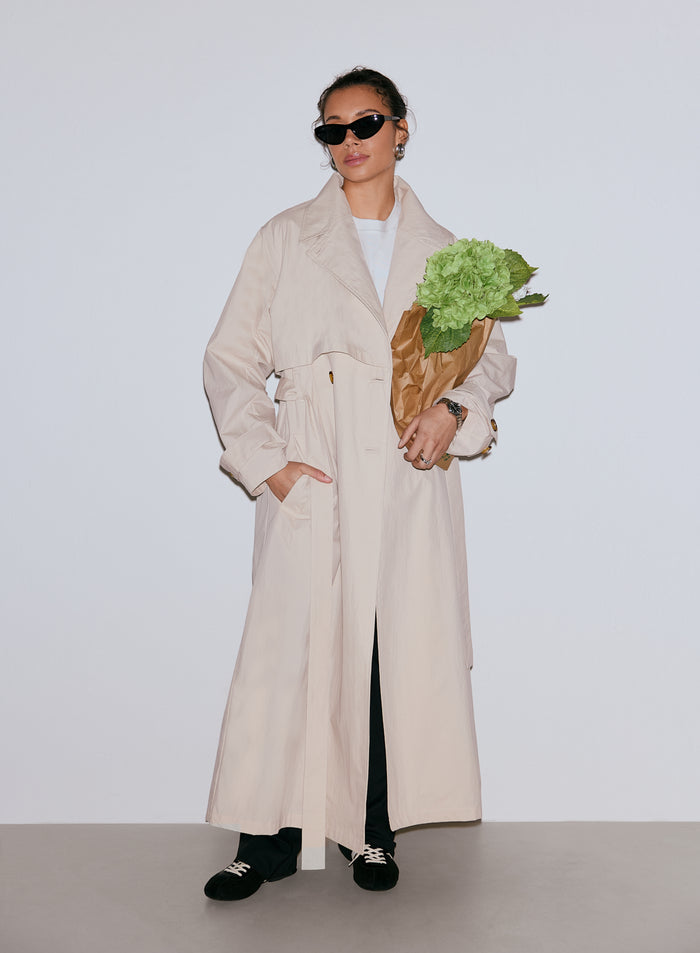 Woman wearing a Café Au Lait Femme Trenchcoat, black sunglasses, and holding a bouquet of green flowers [M-170cm]