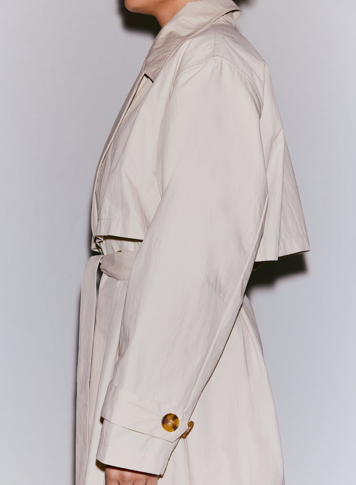 Model wearing a cafe au lait Femme Trenchcoat with a tied belt and tortoise shell button detail [M-170cm]