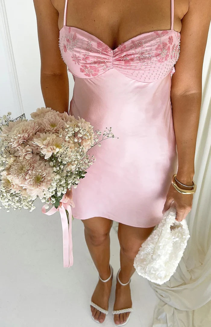 Close-up of the pink satin mini dress with a ruched, beaded floral bust and thin spaghetti straps