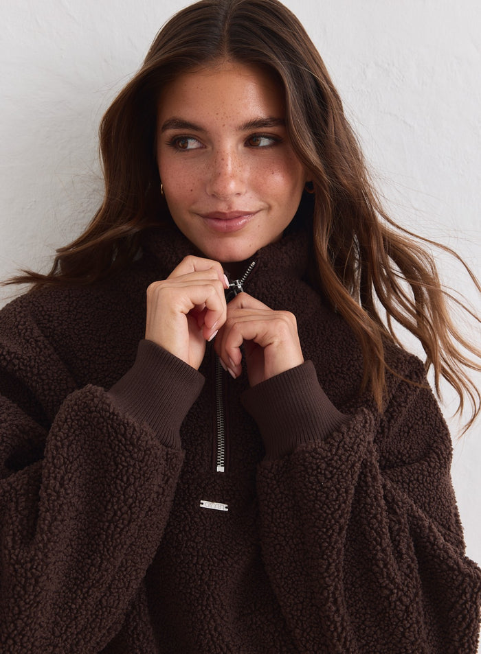 Close-up of a woman wearing a chocolate brown pile fleece half-zip from aim'n. [xs-178cm]