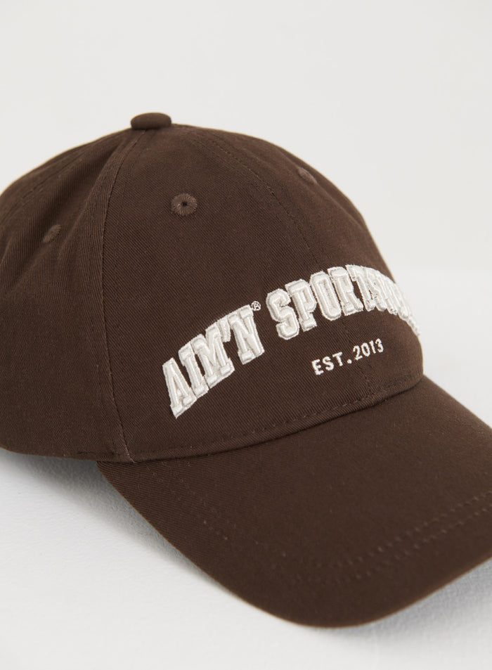 Chocolate brown cotton varsity cap with white embroidered aim'n logo and establishment date.