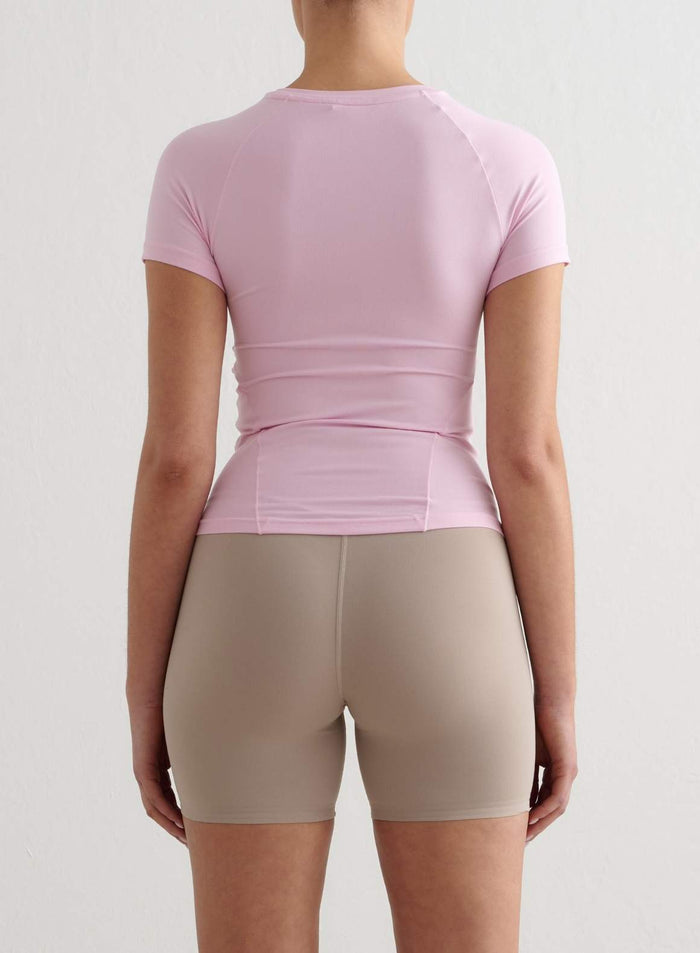 Back view of a light pink aim'n Soft Basic Short Sleeve workout top with a buttery-soft feel.