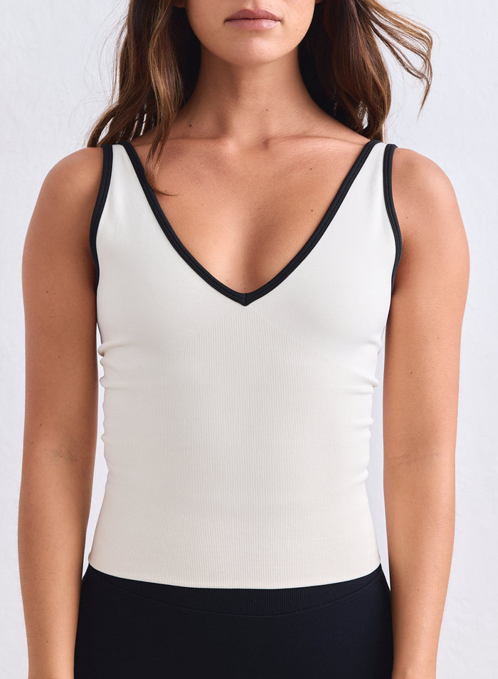 Cream aim'n shape seamless deep cut singlet with black trim and a supportive, ribbed texture. [XS-165cm]