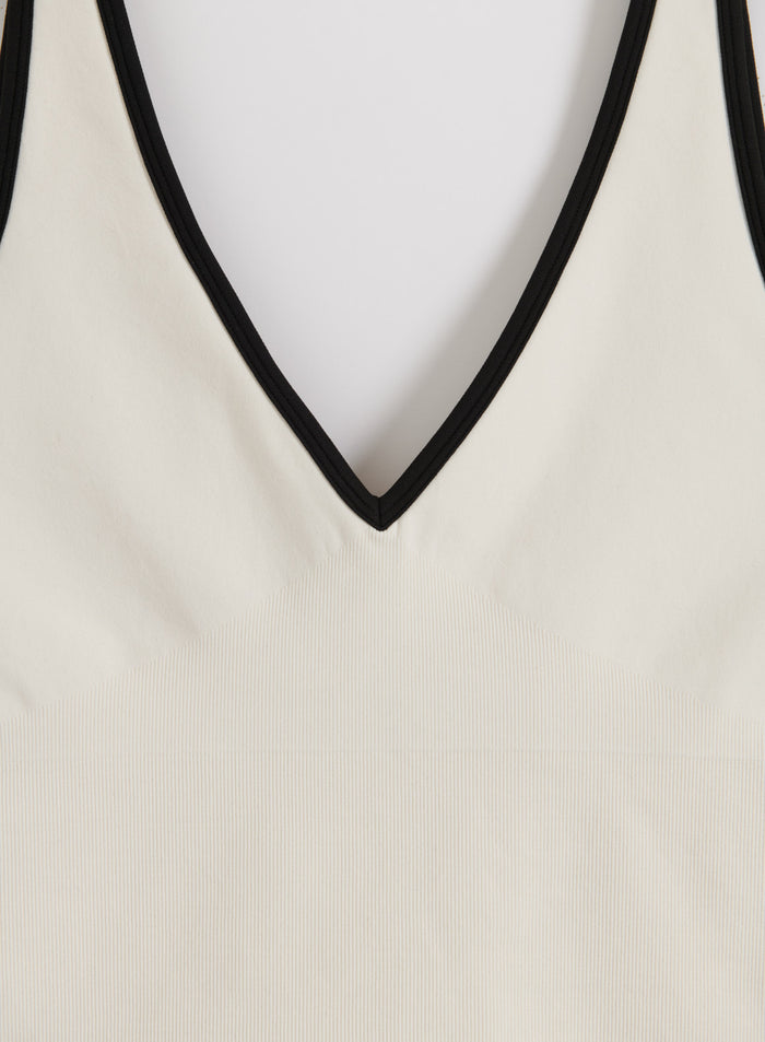 Cream and black aim'n Shape Seamless Deep Cut Singlet close-up showing the deep V-neck and ribbed texture.